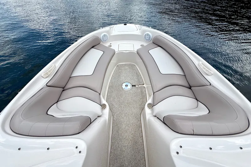Slide: The Image of 2003 Sea Ray 240 Sundeck boat interior with cushioned seating, on calm water. - 19