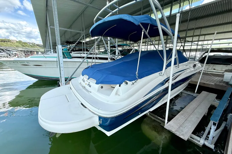 Slide: The Image of 2003 Sea Ray 240 Sundeck boat docked with blue cover and canopy. - 9