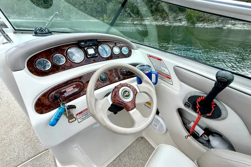 Slide: The Image of 2003 Sea Ray 240 Sundeck helm with gauges, steering wheel, and throttle control. - 21