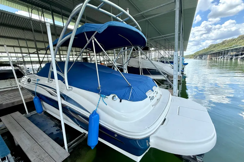 Slide: The Image of 2003 Sea Ray 240 Sundeck boat docked under a covered marina with blue canopy. - 10