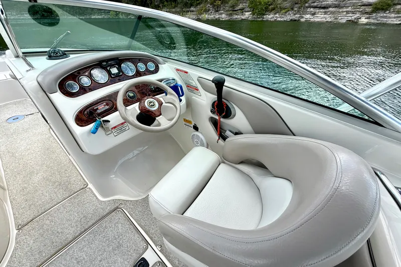 Slide: The Image of 2003 Sea Ray 240 Sundeck cockpit with steering wheel and control panel by the water. - 20
