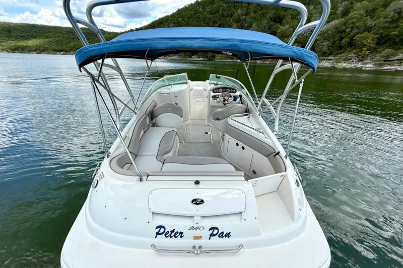 Slide: The Image of 2003 Sea Ray 240 Sundeck boat with blue canopy on a serene lake. - 16