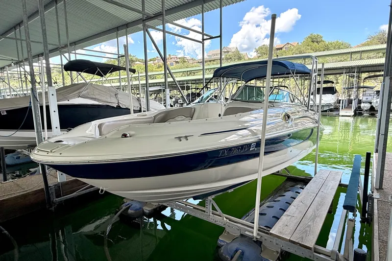 Slide: The Image of 2003 Sea Ray 240 Sundeck boat docked in a marina under a covered structure. - 12