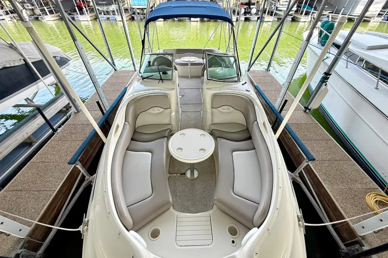 Slide: The Image of 2003 Sea Ray 240 Sundeck boat docked, featuring spacious seating and a central table. - 23