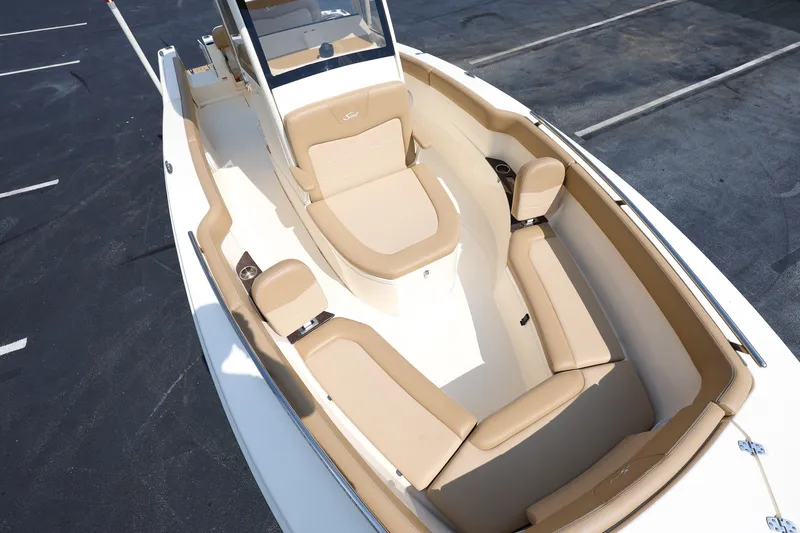 Slide: The Image of 2019 Scout 235 XSF boat with beige seating and sleek design in a parking lot. - 17