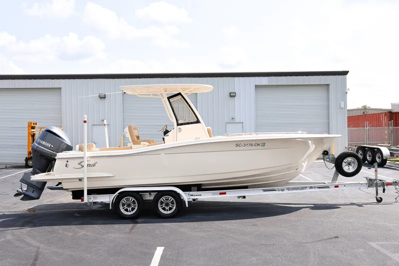 The Image of 2019 Scout 235 XSF boat on trailer, parked outside industrial building. - 1