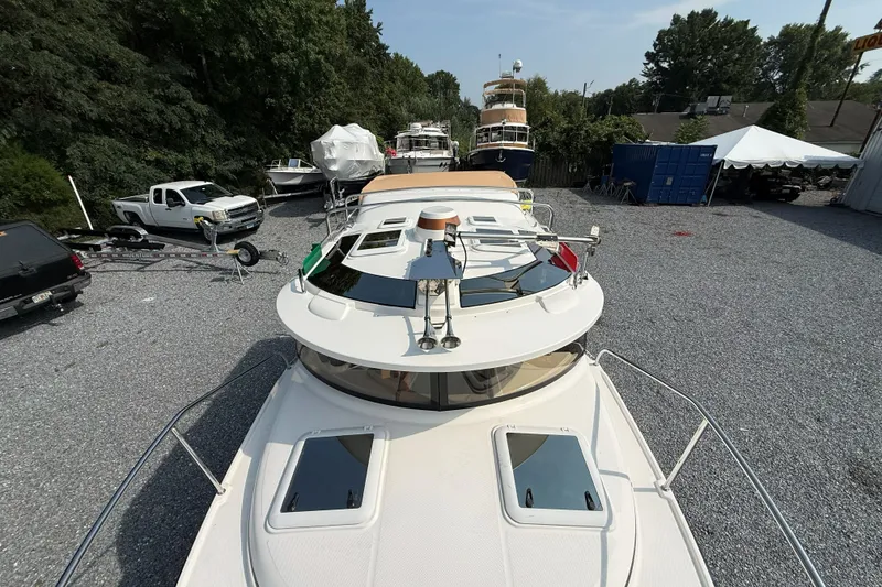 Slide: The Image of 2019 Ranger Tugs R-23 boat parked in a gravel lot with surrounding vehicles. - 16