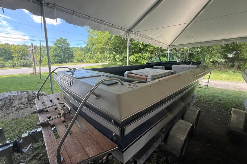 Slide: The Image of 1984 Century Coronado boat under a tent, parked on a trailer, surrounded by greenery. - 17