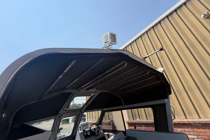 Slide: The Image of 2016 Weldcraft 220 Maverick DV boat canopy and dashboard, parked near a metal building. - 20