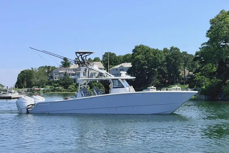 The Image of 2026 Freeman 42LR boat cruising on a serene lake with waterfront homes in the background. - 1