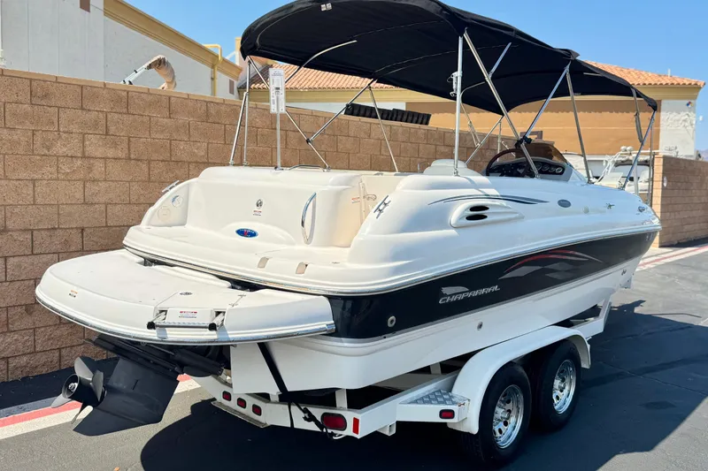 Slide: The Image of 2004 Chaparral Sunesta 212 boat with black canopy on a trailer, parked outdoors. - 4