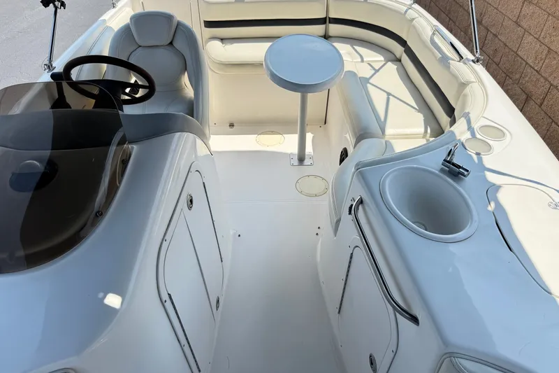 Slide: The Image of 2004 Chaparral Sunesta 212 boat interior with seating, steering wheel, and sink. - 18
