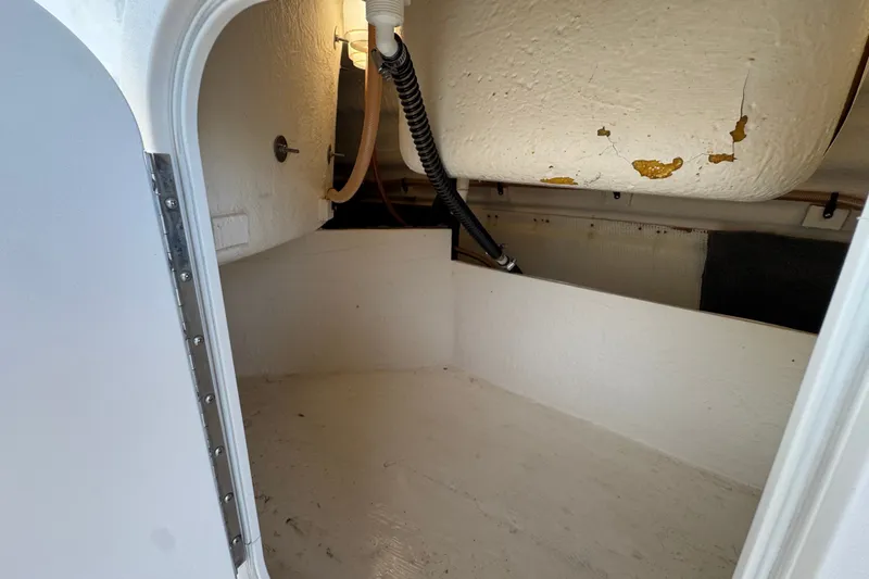 Slide: The Image of 2004 Chaparral Sunesta 212 boat interior storage compartment with visible wear and piping. - 21