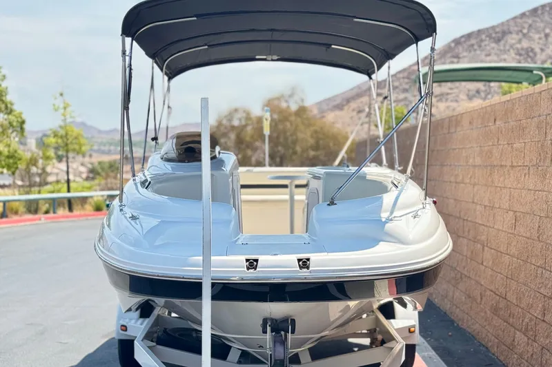 Slide: The Image of 2004 Chaparral Sunesta 212 boat with canopy, parked on a trailer, scenic background. - 2