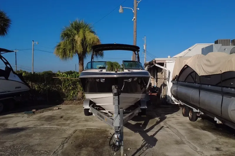 Slide: The Image of 2018 Regal 2300 Bowrider boat on trailer, parked outdoors under clear blue sky. - 8