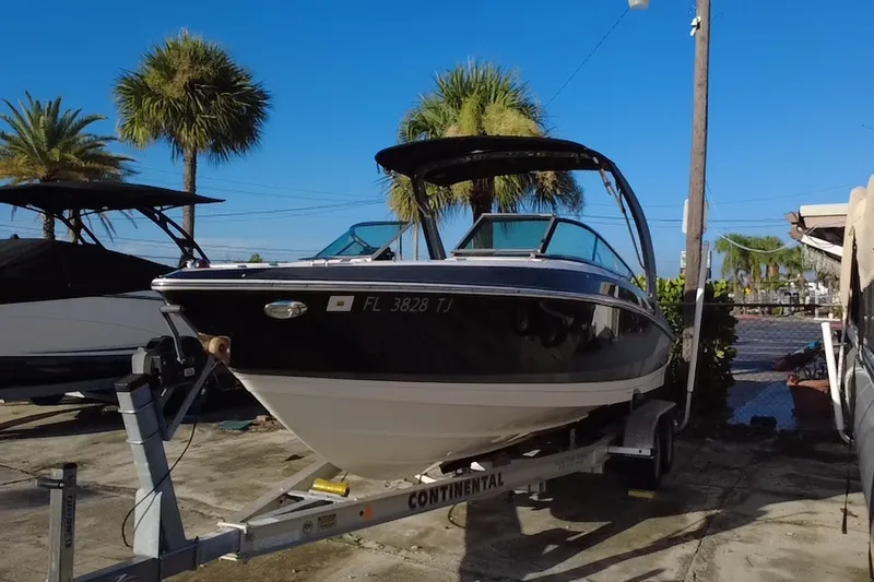 Slide: The Image of 2018 Regal 2300 Bowrider boat on trailer, parked outdoors under clear blue sky. - 7