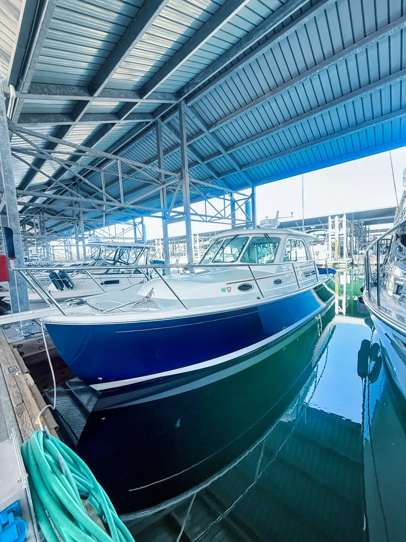 Slide: The Image of A 2016 Back Cove 30 boat docked in a covered marina, surrounded by other boats. - 30