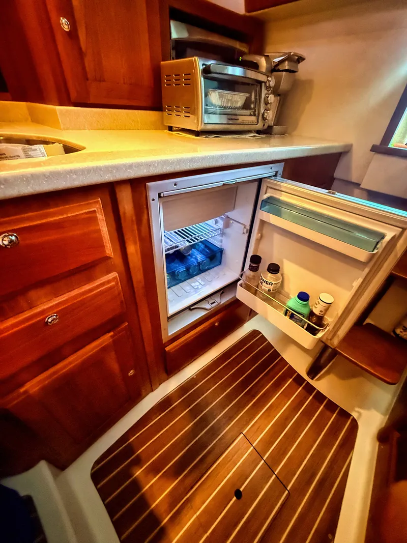Slide: The Image of Compact kitchen with wood flooring, fridge, and appliances in a 2016 Back Cove 30. - 24