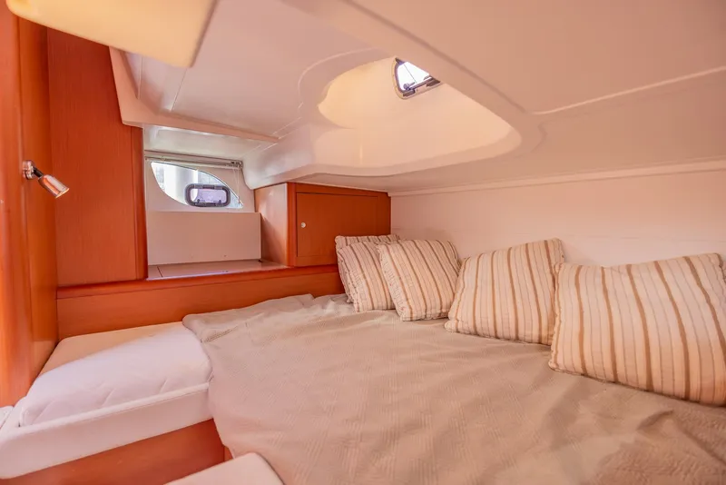 Slide: The Image of Cozy cabin interior of 2013 Beneteau Gran Turismo 38 with striped pillows and wooden accents. - 38