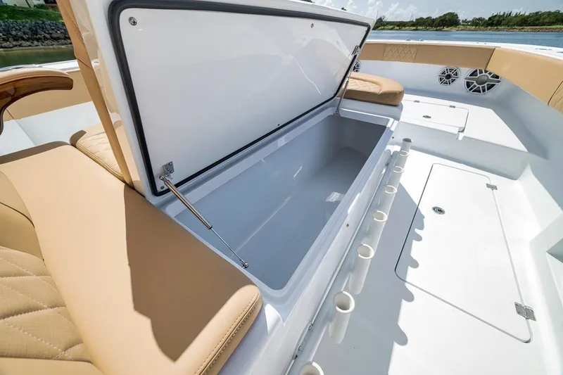 Slide: The Image of Open storage compartment on 2026 Freeman 42LR boat with beige seating and rod holders. - 49