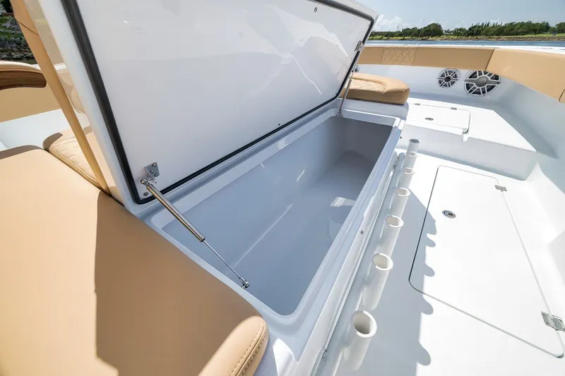 Slide: The Image of Open storage compartment on 2026 Freeman 42LR boat with beige seating and rod holders. - 48