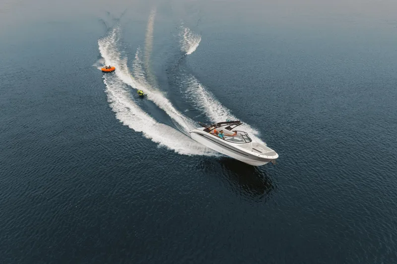 Slide: The Image of A Sea Ray SDX 270 Surf towing two colorful inflatables across calm water. - 38
