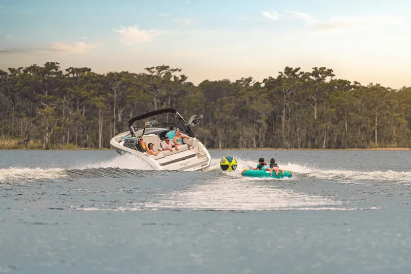 Slide: The Image of A 2027 Sea Ray SDX 270 Surf towing an inflatable tubing ring on a lake. - 20