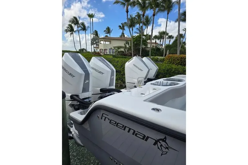 Slide: The Image of 2024 Freeman 47 boat with Mercury engines, palm trees, and a house in the background. - 4