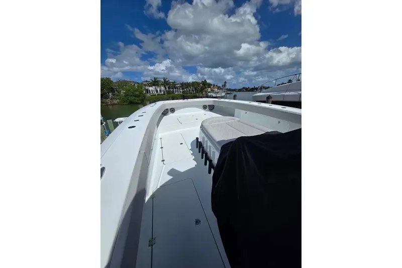 Slide: The Image of 2024 Freeman 47 boat deck under a partly cloudy sky, docked near lush greenery. - 14