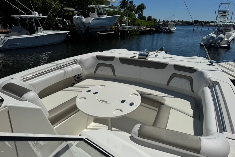 Slide: The Image of 2022 World Cat 296 DC boat interior with seating and table, docked by the water. - 19