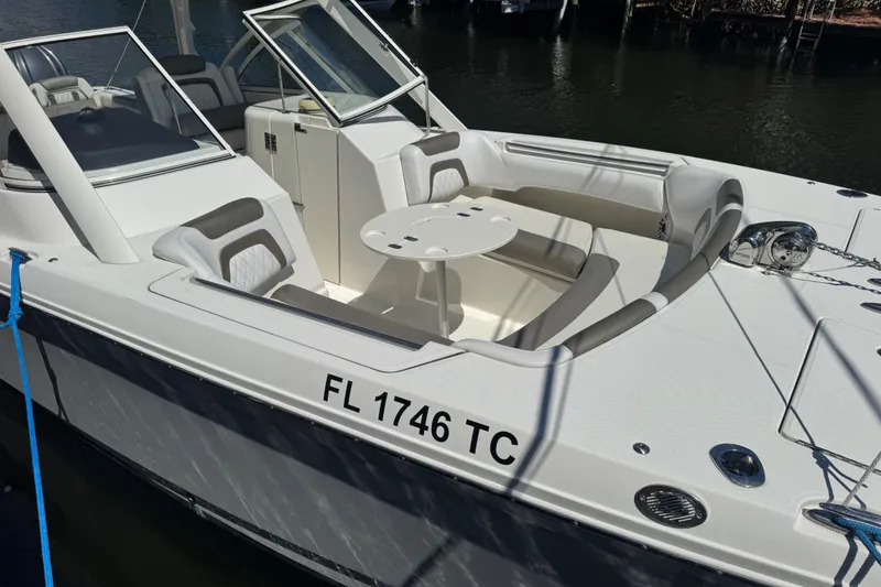 Slide: The Image of 2022 World Cat 296 DC boat with seating area and table, docked on calm water. - 20