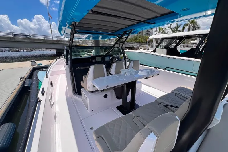 Slide: The Image of 2023 Axopar Brabus 37 Sun-Top boat interior with seating and table, docked by a bridge. - 50