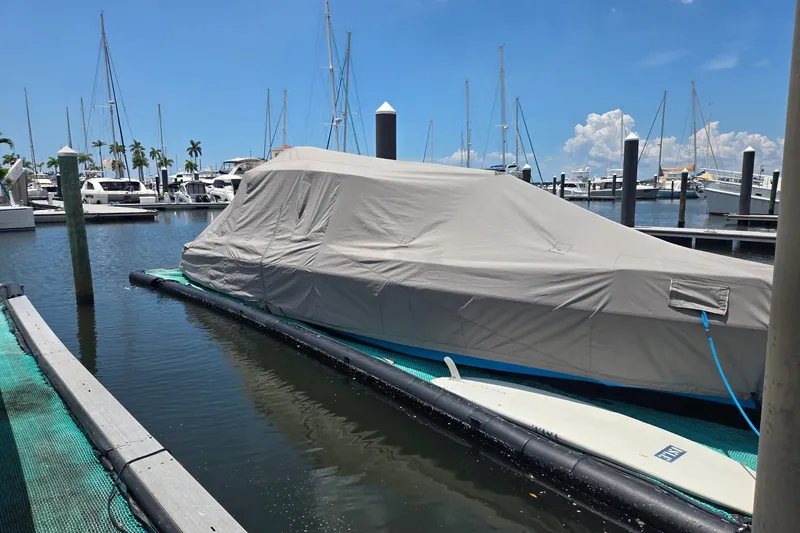 Slide: The Image of 2023 Axopar Brabus 37 Sun-Top covered at marina, surrounded by boats and clear sky. - 72