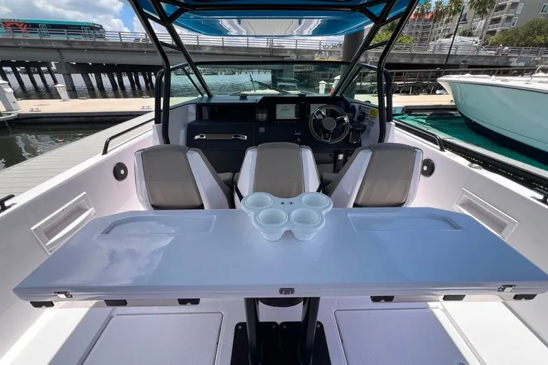 Slide: The Image of 2023 Axopar Brabus 37 Sun-Top boat interior with seating and table, docked by the water. - 44