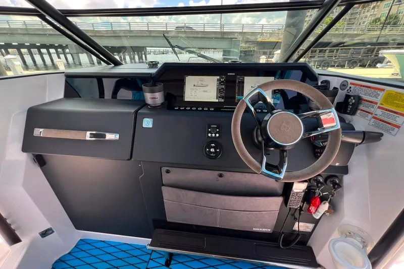 Slide: The Image of 2023 Axopar Brabus 37 Sun-Top boat cockpit with modern steering and navigation controls. - 37