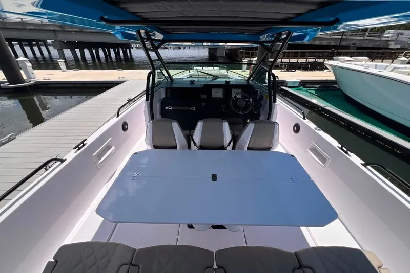 Slide: The Image of 2023 Axopar Brabus 37 Sun-Top boat interior with seating and table at a marina. - 33