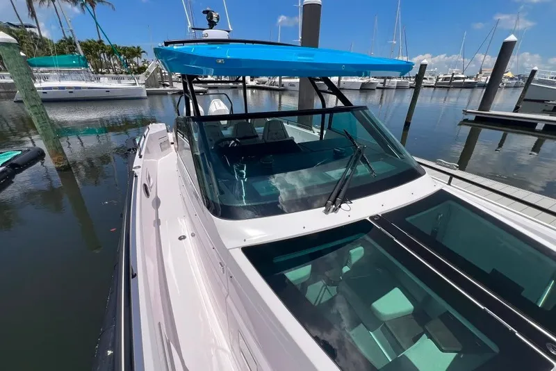 Slide: The Image of 2023 Axopar Brabus 37 Sun-Top boat docked in a marina under clear blue skies. - 60