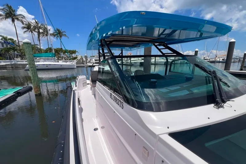 Slide: The Image of 2023 Axopar Brabus 37 Sun-Top boat docked at marina under blue sky. - 57