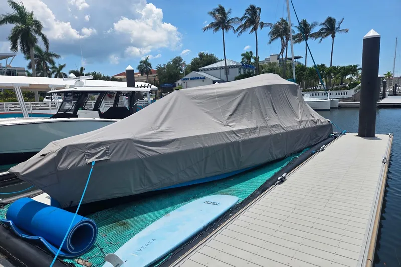 Slide: The Image of Covered 2023 Axopar Brabus 37 Sun-Top docked, surrounded by palm trees and clear skies. - 73