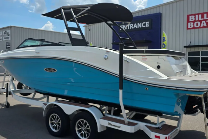 Slide: The Image of 2023 Sea Ray SPX 230 boat on trailer, blue and white exterior, parked outside dealership. - 2