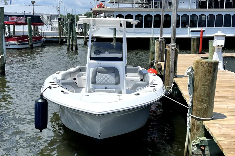 Slide: The Image of 2024 NauticStar 222L Offshore boat docked at marina, front view. - 2