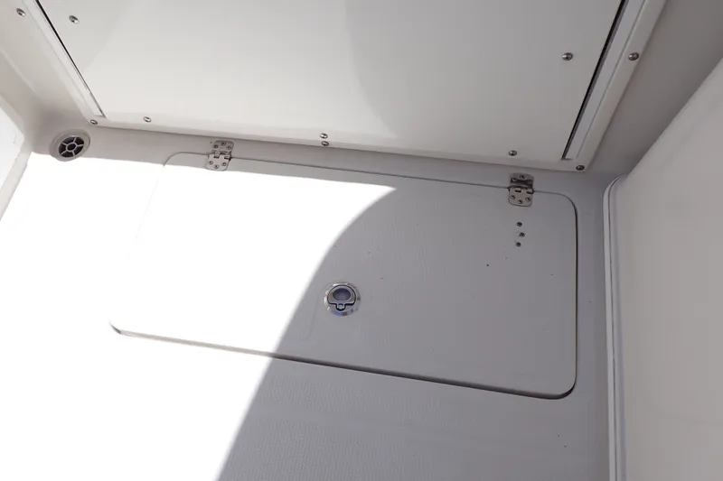 Slide: The Image of 2019 Sailfish 245 DC boat storage compartment with secure latch and clean white finish. - 66
