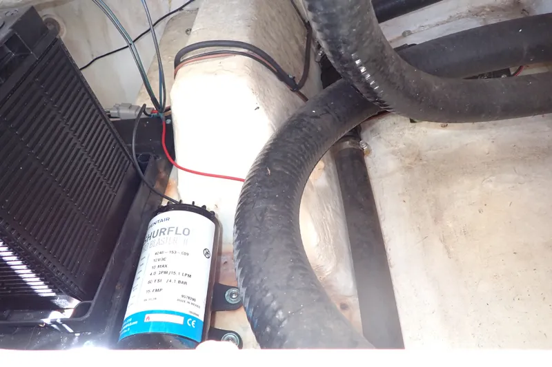 Slide: The Image of 2019 Sailfish 245 DC boat interior showing Shurflo pump and wiring components. - 76