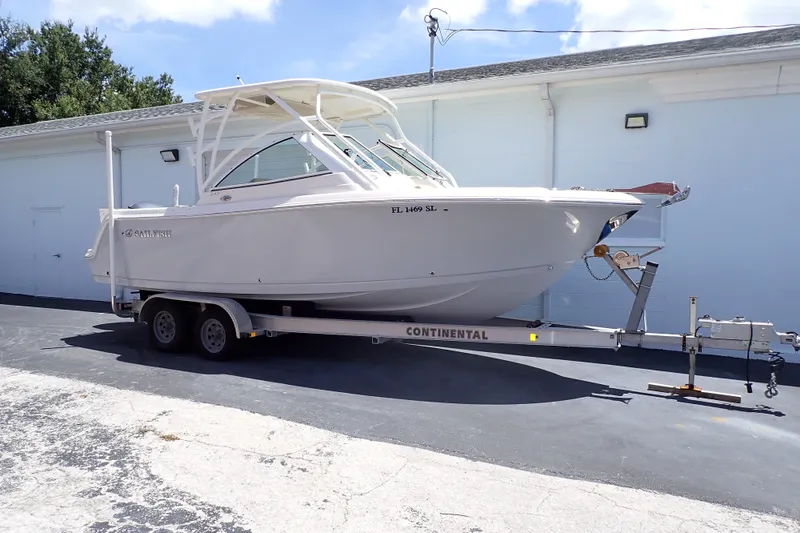 The Image of 2019 Sailfish 245 DC boat on trailer, parked outdoors near a building. - 0