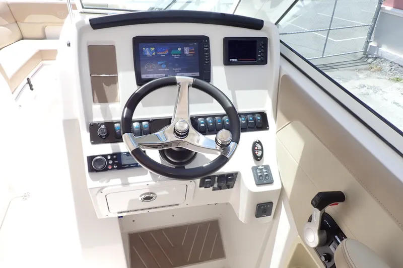 Slide: The Image of 2019 Sailfish 245 DC boat dashboard with steering wheel and control panel. - 21