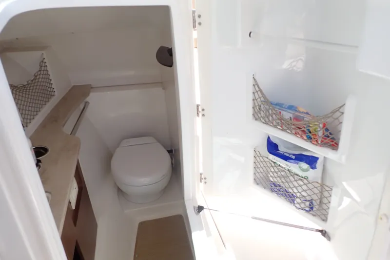 Slide: The Image of 2019 Sailfish 245 DC boat interior with compact bathroom and storage nets. - 32