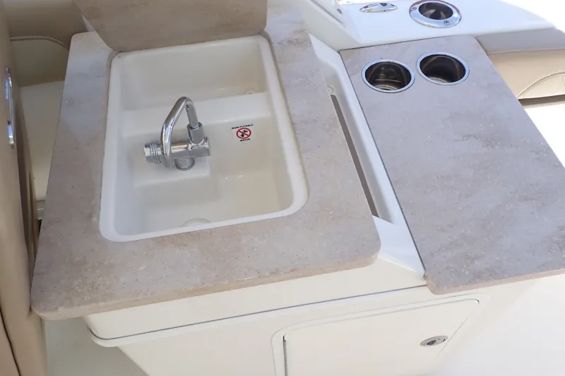 Slide: The Image of 2019 Sailfish 245 DC boat sink with faucet and cup holders on beige countertop. - 62
