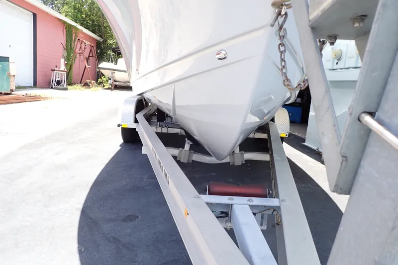 Slide: The Image of 2019 Sailfish 245 DC boat on trailer, parked outdoors near a pink building. - 121