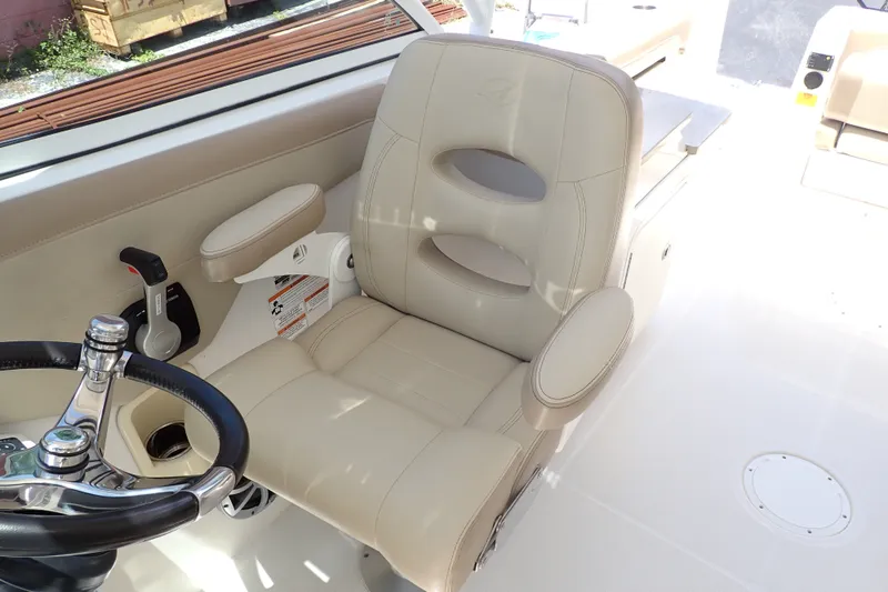 Slide: The Image of Captain's chair on 2019 Sailfish 245 DC boat, featuring beige upholstery and steering wheel. - 90