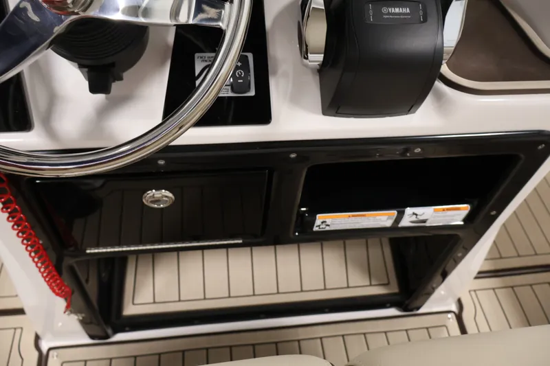 Slide: The Image of 2026 Yamaha Boats 252 FSH Sport steering console with controls and storage compartment. - 32